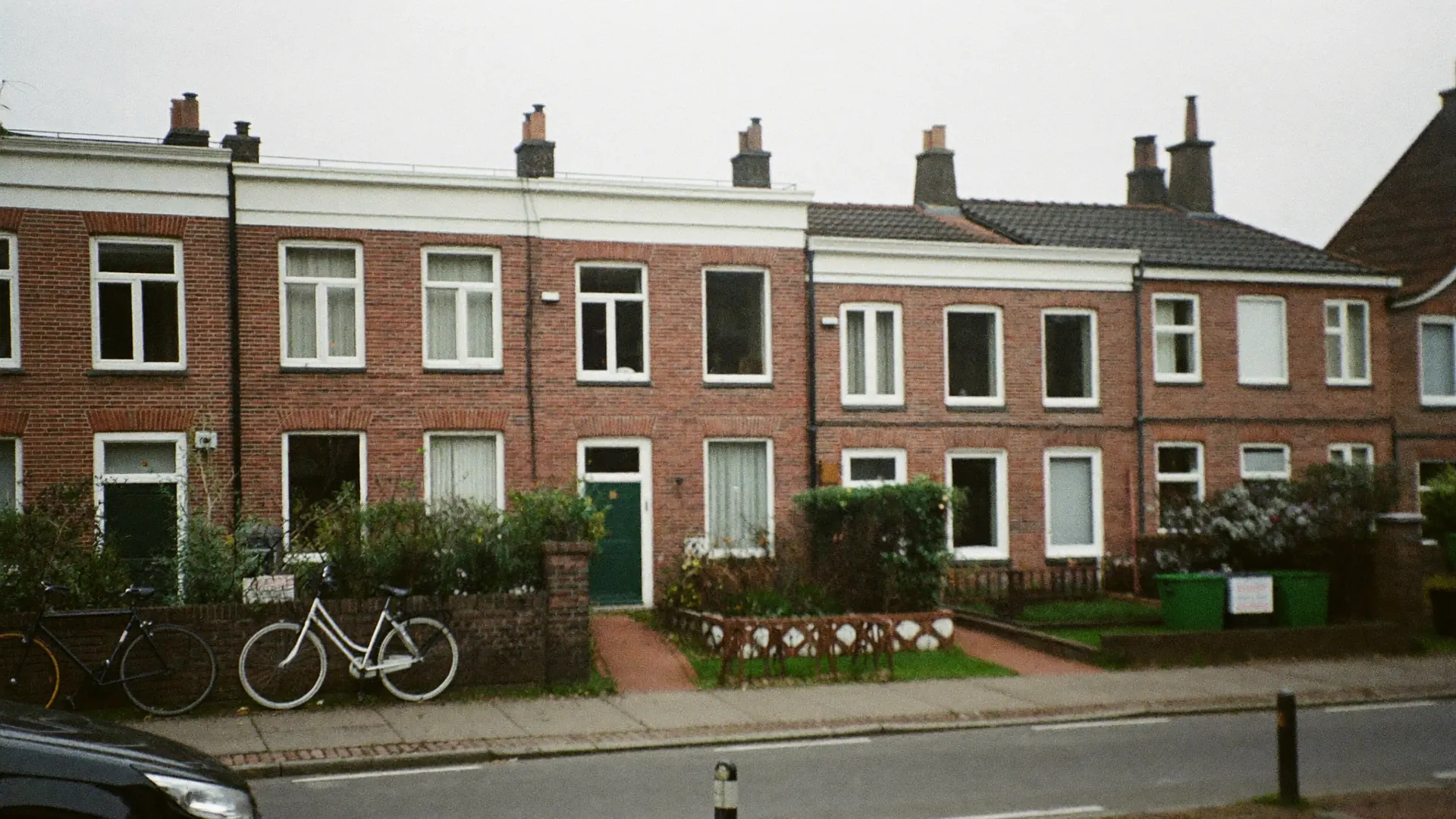 Straat met bakstenen rijtjeshuizen en witte kozijnen